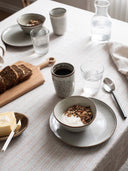 Taranto kopp Tell Me More på ett dukat frukostbord med galette dricksglas och en randig duk